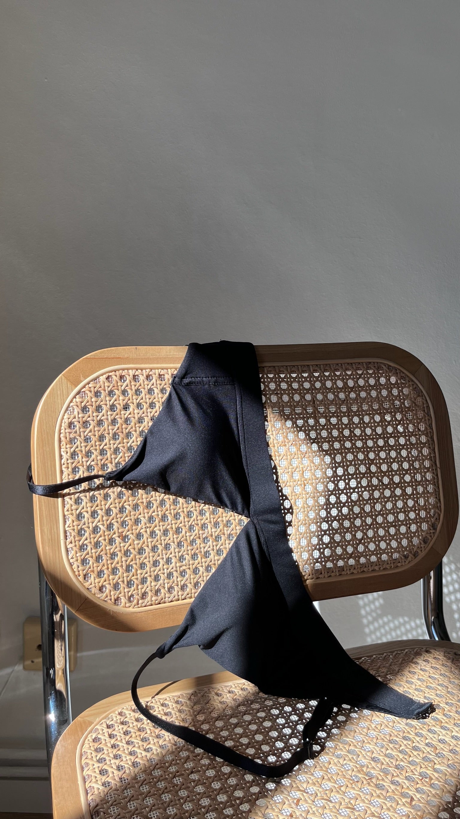 Bra hanging off of a chair showing the stitching and fabric details.